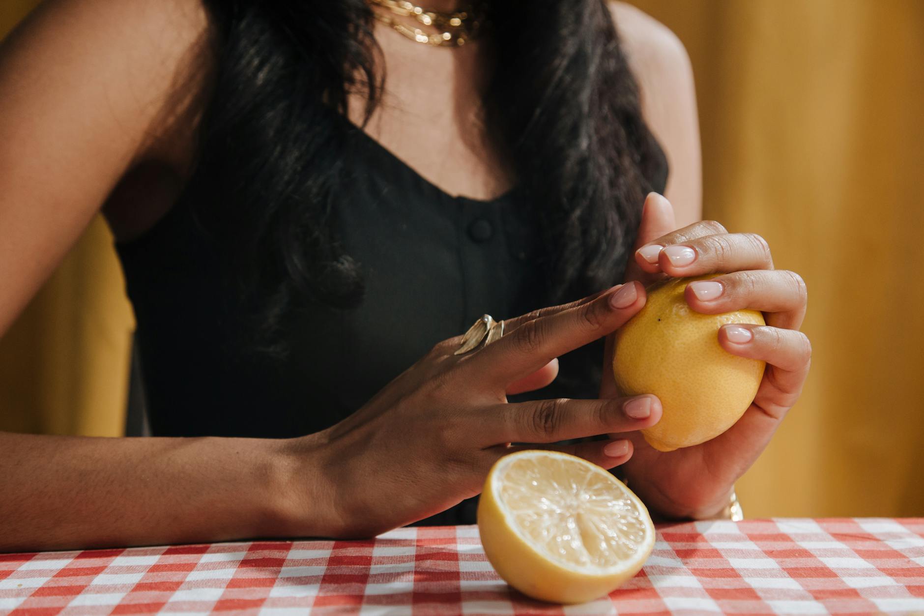A close-up of hands holding a fresh lemon at a dining table, symbolizing clarity and focus